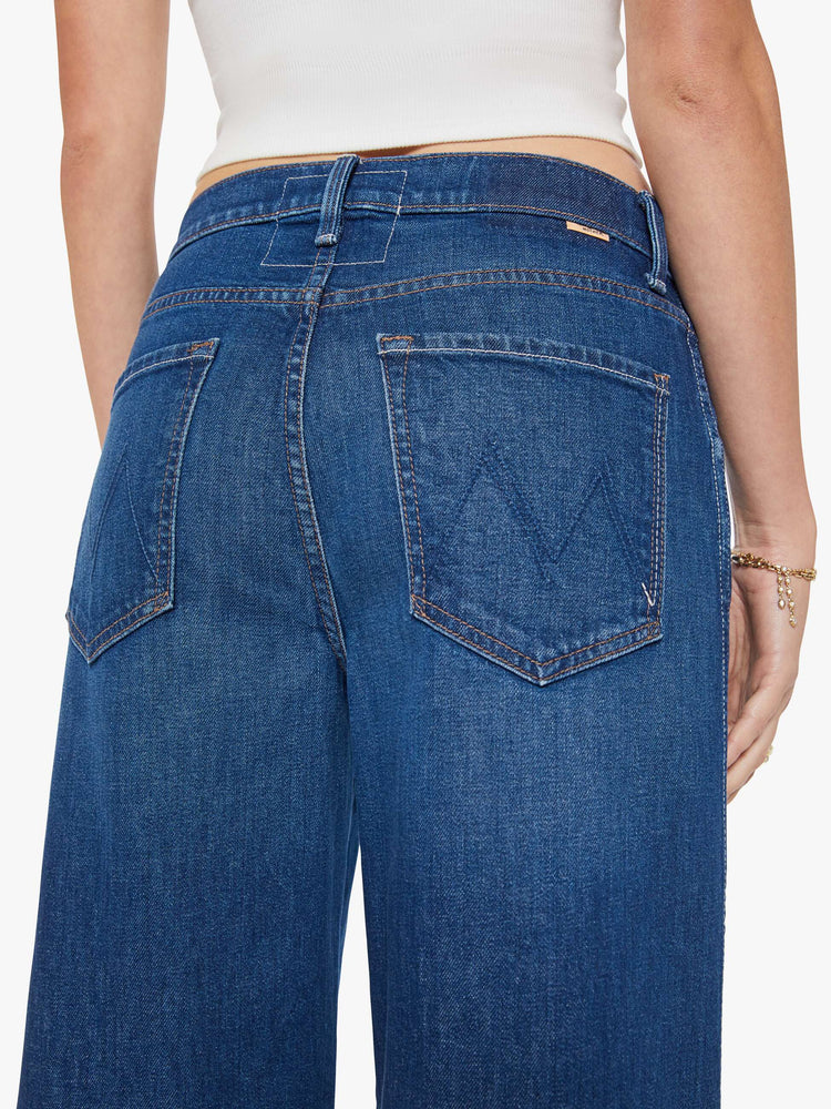 Close up view of a woman in a dark blue jeans designed to sit lower on the hips with an ankle-length inseam, zip fly, clean hem and slightly tapered leg.
