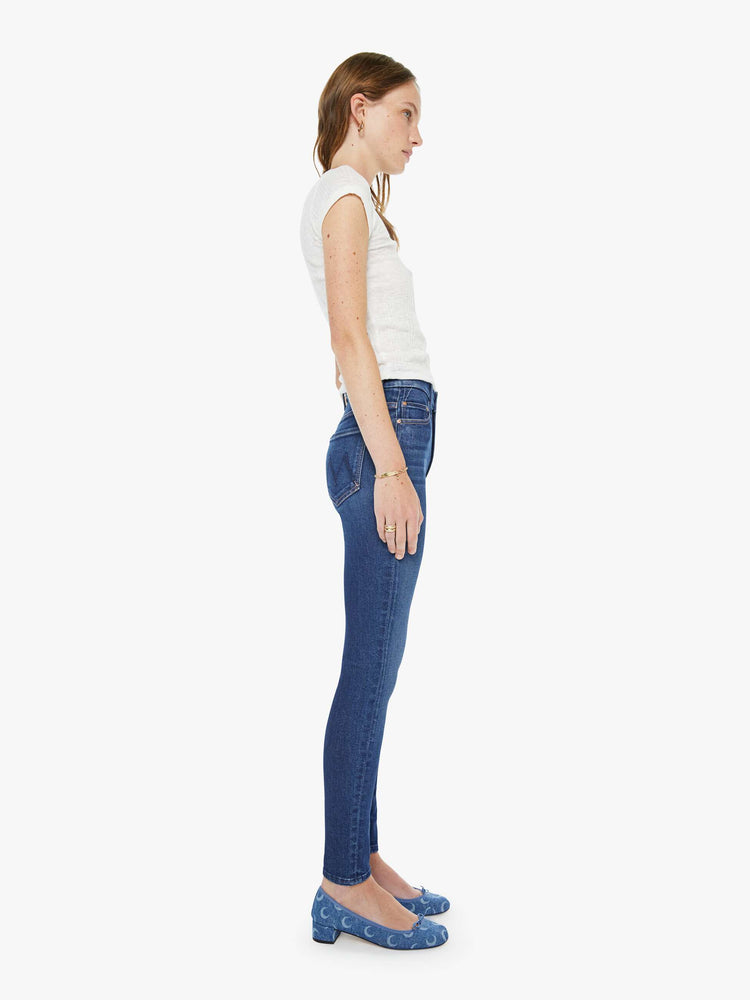 Side view of a woman in a skinny high rise jean with a zip fly, 29-inch inseam and a clean hem.