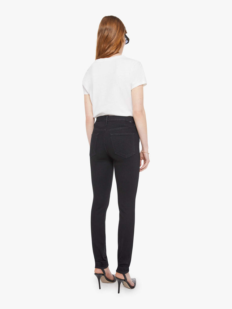 Back view of a woman in a black skinny with a high rise with a 29-inch inseam and a clean hem.