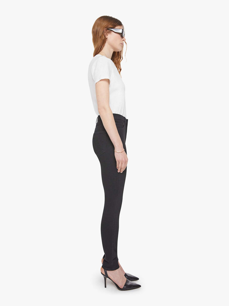 Side view of a woman in a black skinny with a high rise with a 29-inch inseam and a clean hem.