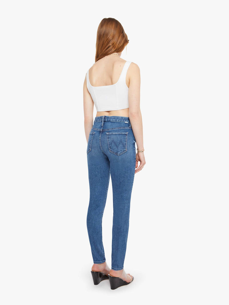 Back view of a woman in a med blue skinny with a high rise with a zip fly, 29-inch inseam and a clean hem. 