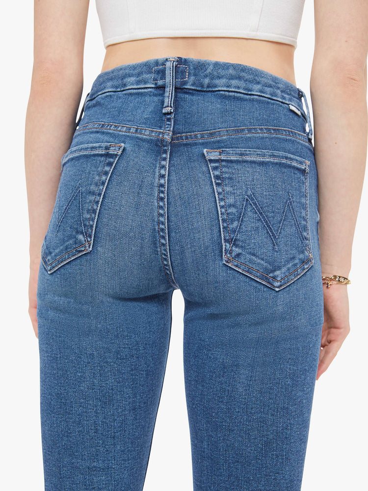 Back view of a woman in a med blue skinny with a high rise with a zip fly, 29-inch inseam and a clean hem. 