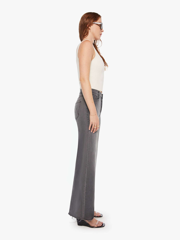 Side view of women's grey high waisted wide leg jean with a frayed hem.