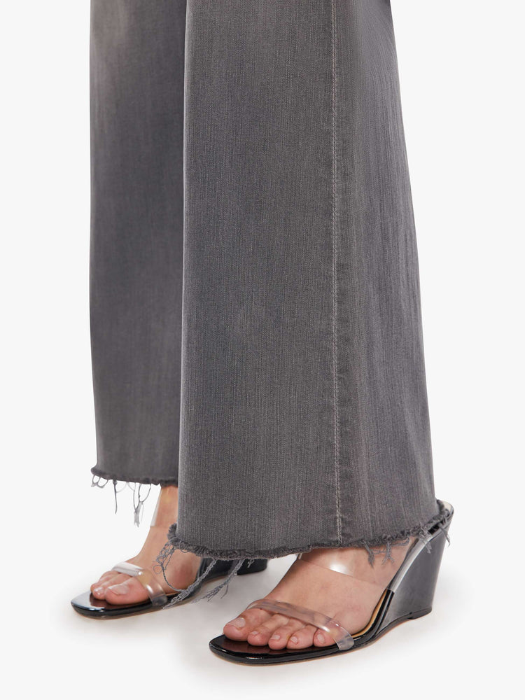 Detail view of women's grey high waisted wide leg jean with a frayed hem.