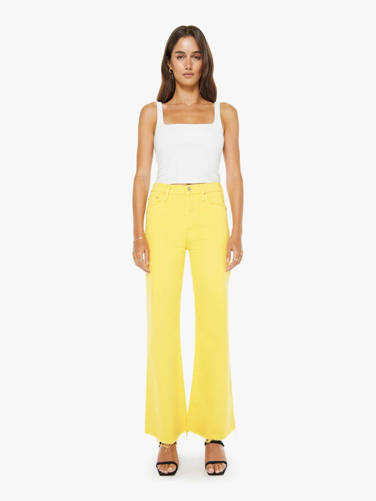 Front view of a woman in yellow high-waisted wide-leg jeans with a button fly, 31-inch inseam and a frayed hem.