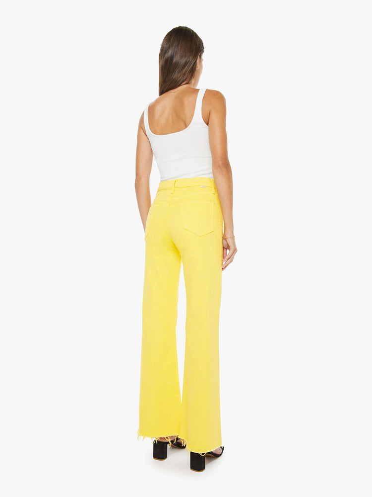 Back view of a woman in yellow high-waisted wide-leg jeans with a button fly, 31-inch inseam and a frayed hem.