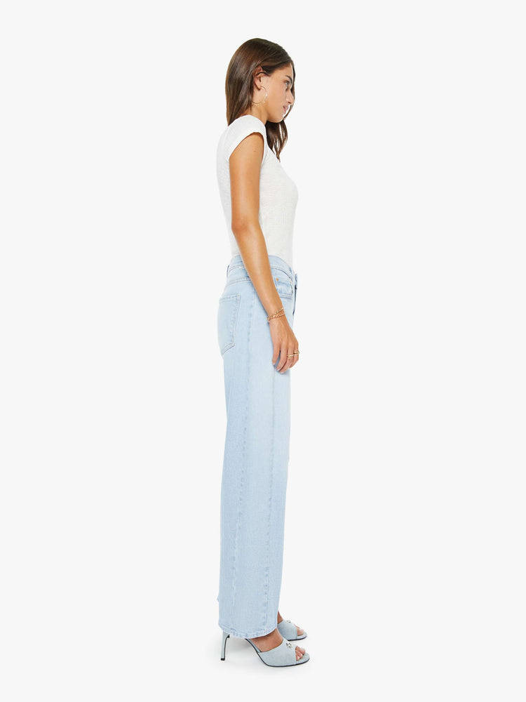 Side view of a woman in a light blue mid-rise jeans with a wide, curved leg, zip fly and a 29-inch inseam with a clean hem.