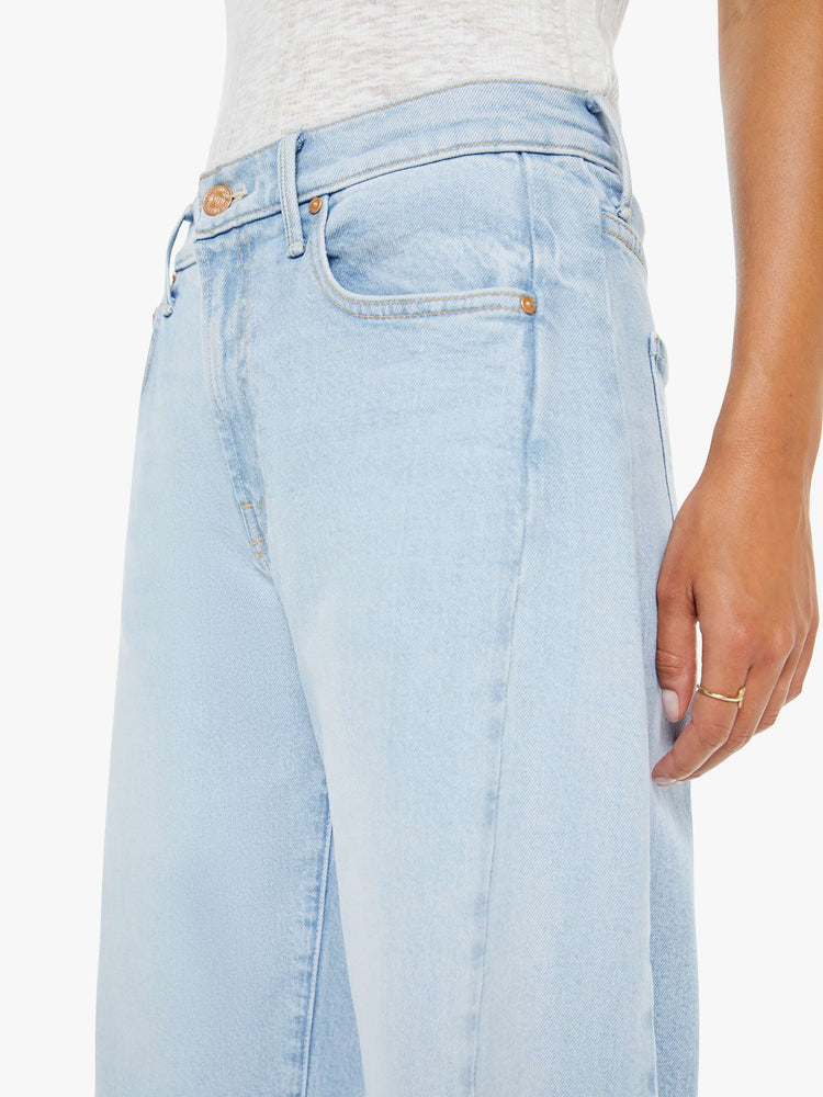 Close up view of a woman in a light blue mid-rise jeans with a wide, curved leg, zip fly and a 29-inch inseam with a clean hem.