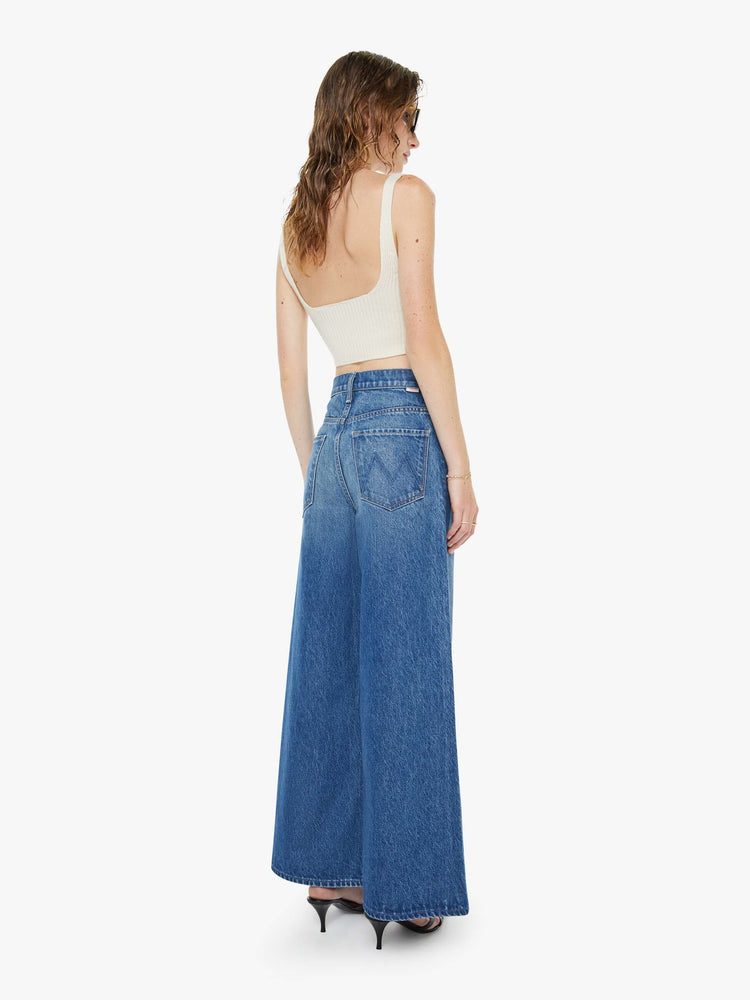 Back view of a woman in a mid blue  high-waisted pants have a zip fly, loose, wide leg with seamed details down the front and a 28.5-inch inseam with a clean hem. 