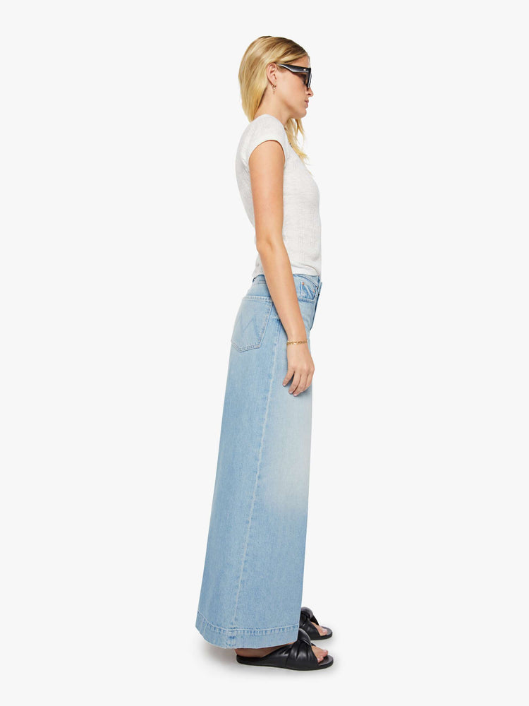 Side view of a woman in a light blue mid-rise wide-leg jeans with a zip fly, long 32-inch inseam and a clean, wide hem.