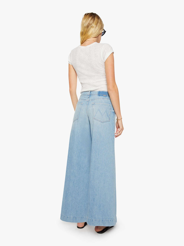 Back view of a woman in a light blue mid-rise wide-leg jeans with a zip fly, long 32-inch inseam and a clean, wide hem.