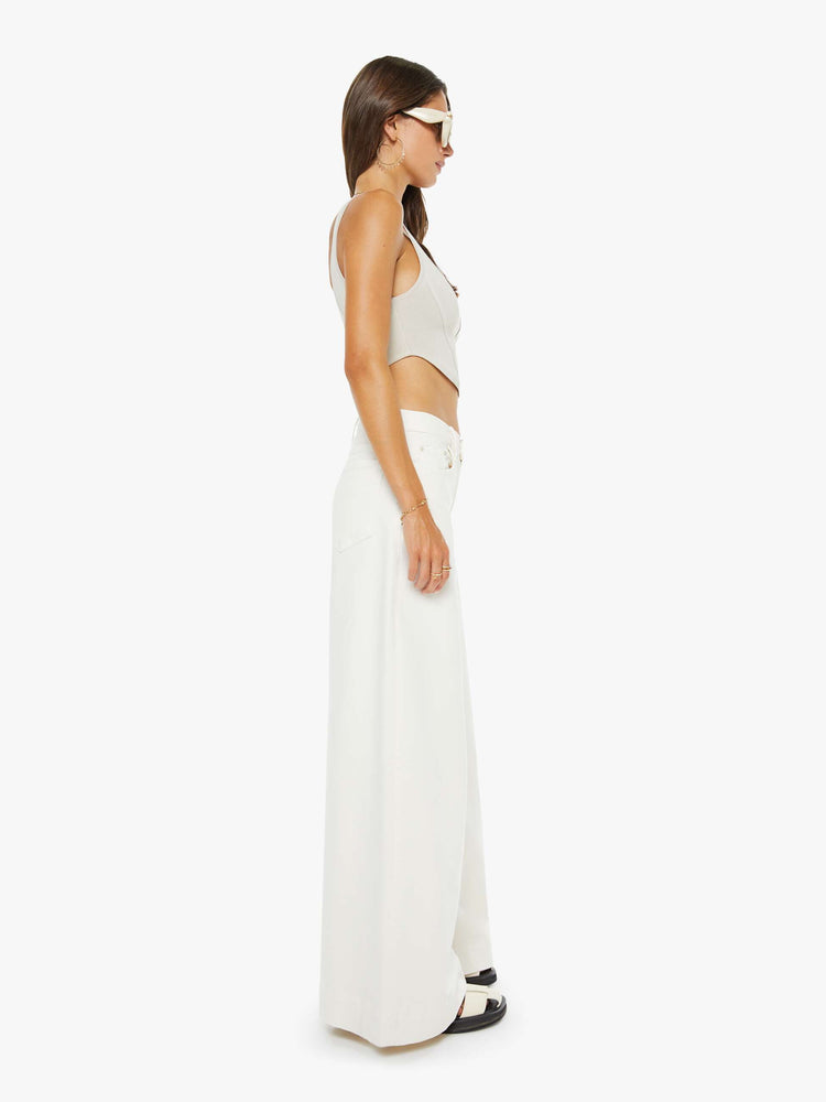 Side view of a woman in an off white mid-rise wide-leg jeans with a zip fly, long 32-inch inseam and a clean, wide hem.
