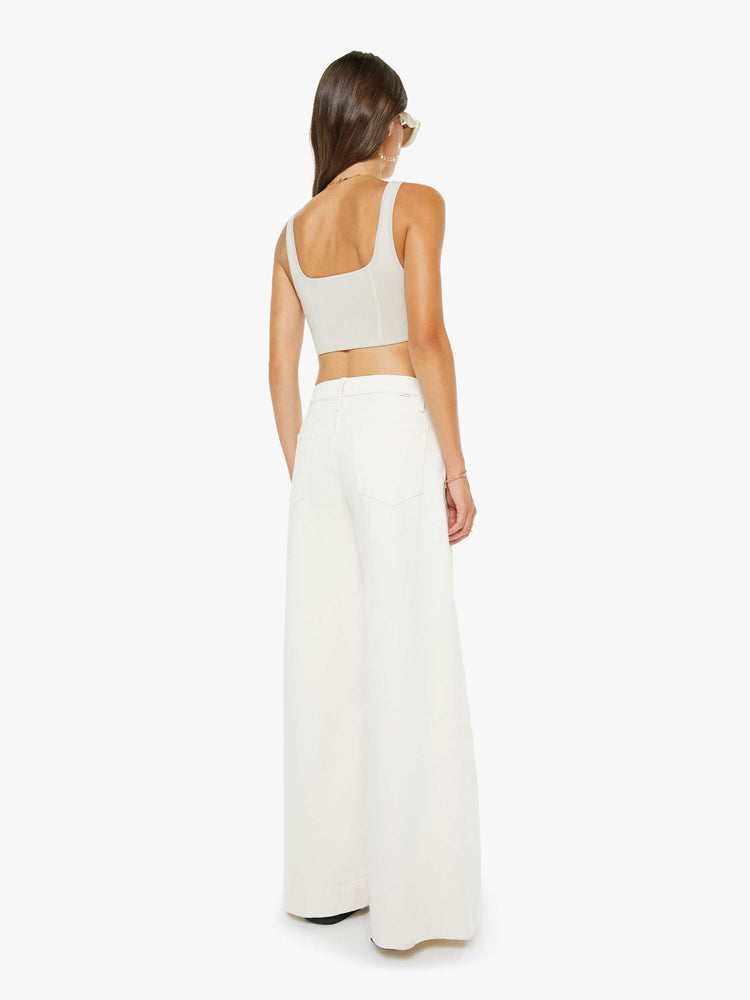 Back view of a woman in an off white mid-rise wide-leg jeans with a zip fly, long 32-inch inseam and a clean, wide hem.