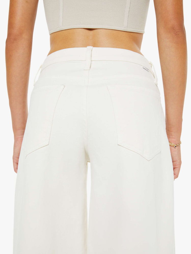 Close up view of a woman in an off white mid-rise wide-leg jeans with a zip fly, long 32-inch inseam and a clean, wide hem.