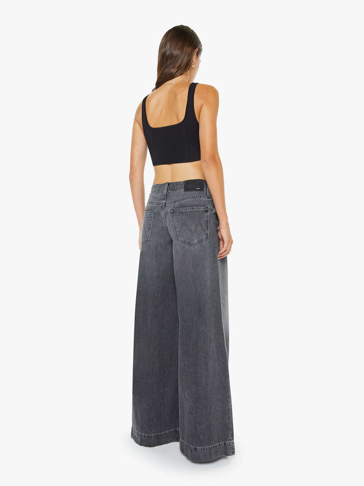 Back view of a woman in a faded black mid-rise wide-leg jeans with a zip fly, long 34-inch inseam and a clean, wide hem.