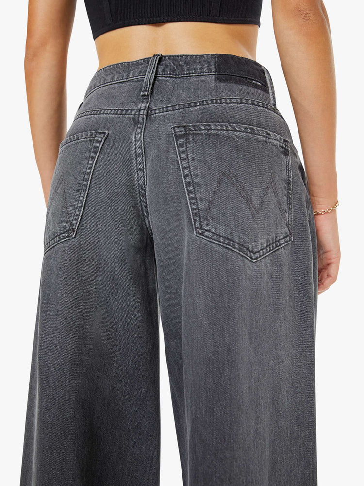 Close up view of a woman in a faded black mid-rise wide-leg jeans with a zip fly, long 34-inch inseam and a clean, wide hem.