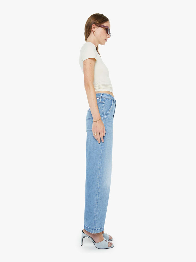 Side view of a woman in a light blue super high-waisted pants with a loose, straight leg, zip fly, utility-inspired patch pockets, hammer loop and an ankle-length inseam with a clean hem.
