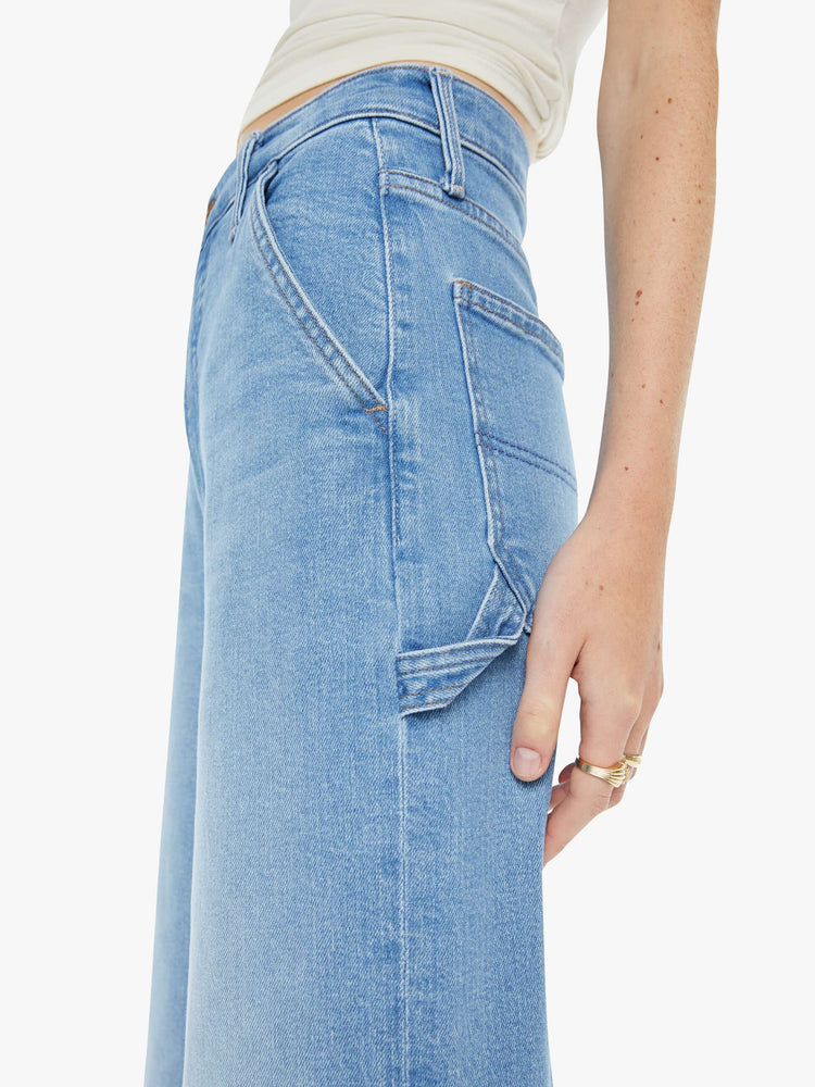 Close up view of a woman in a light blue super high-waisted pants with a loose, straight leg, zip fly, utility-inspired patch pockets, hammer loop and an ankle-length inseam with a clean hem.