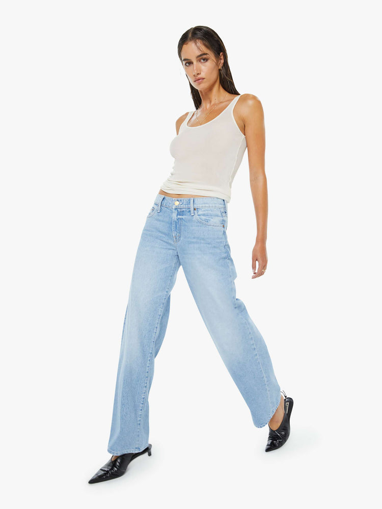 Walking view of a woman in a light blue mid-rise jeans have a long 32-inch inseam and a clean hem.