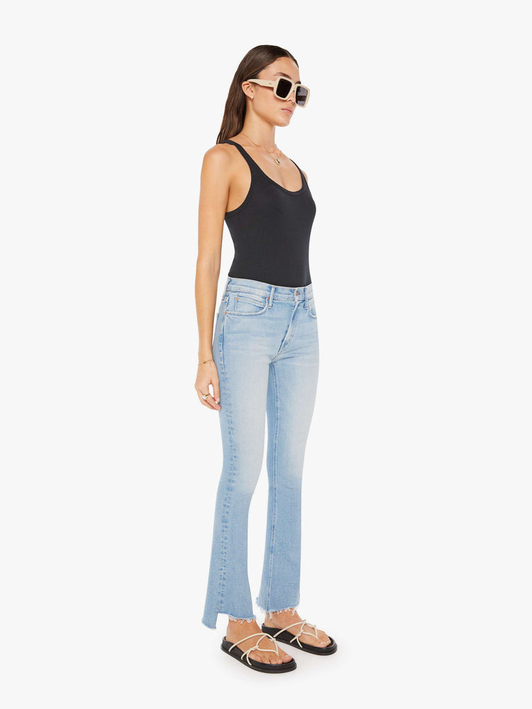 Front view of a womens light blue denim featuring a mid rise, flare leg, and a crop step fray hem.
