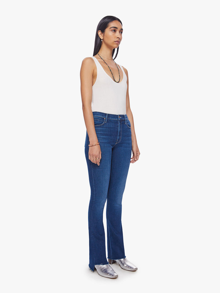 Front view of woman mid-rise flare with a 31-inch inseam and a frayed step-hem in a dark blue wash.