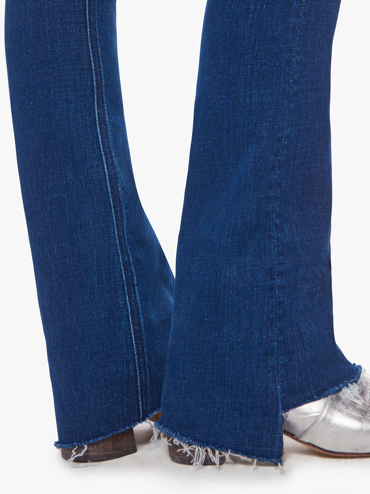 Close up hem view of woman mid-rise flare with a 31-inch inseam and a frayed step-hem in a dark blue wash.