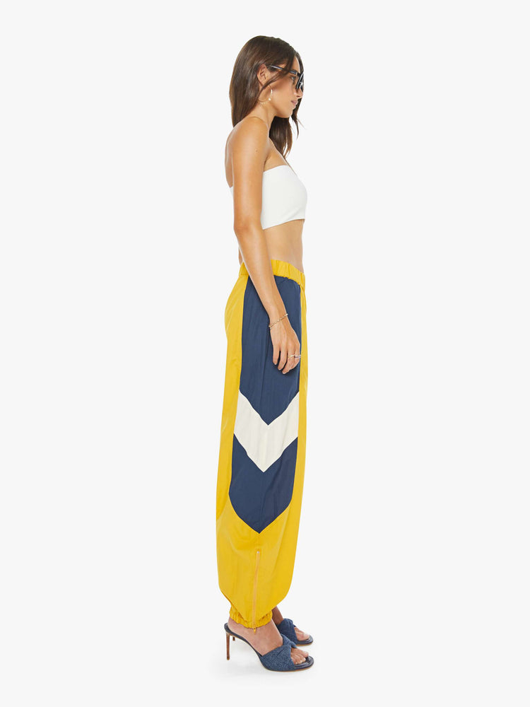 Side view of a woman high-rise sweatpants with an elastic waistband, slit pockets and a loose, straight leg with a long inseam and elastic hems.