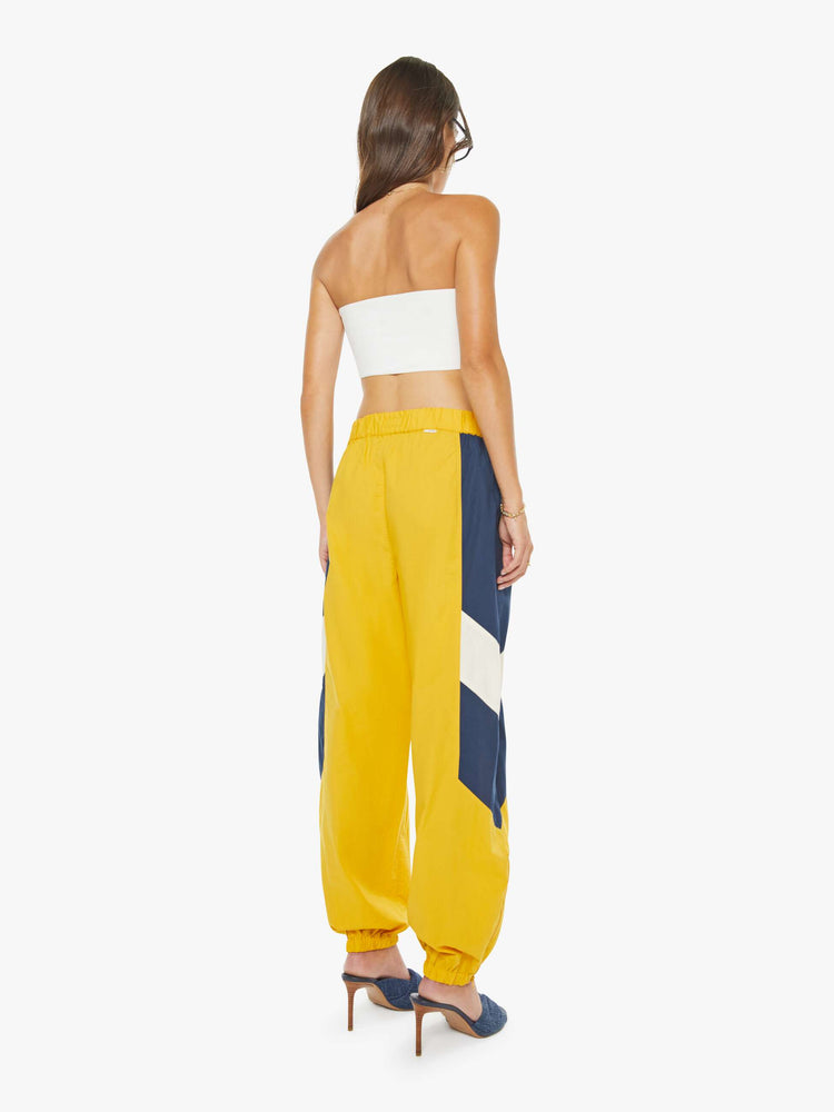 Back view of a woman high-rise sweatpants with an elastic waistband, slit pockets and a loose, straight leg with a long inseam and elastic hems.