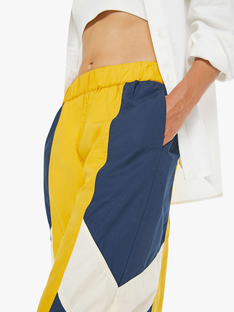 Close up view of a woman high-rise sweatpants with an elastic waistband, slit pockets and a loose, straight leg with a long inseam and elastic hems.