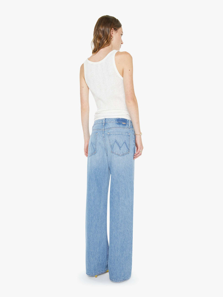 Back view of a woman in a light blue high-waisted wide leg jeans with a zip fly, a long 32-inch inseam and loose, low-slung fit.