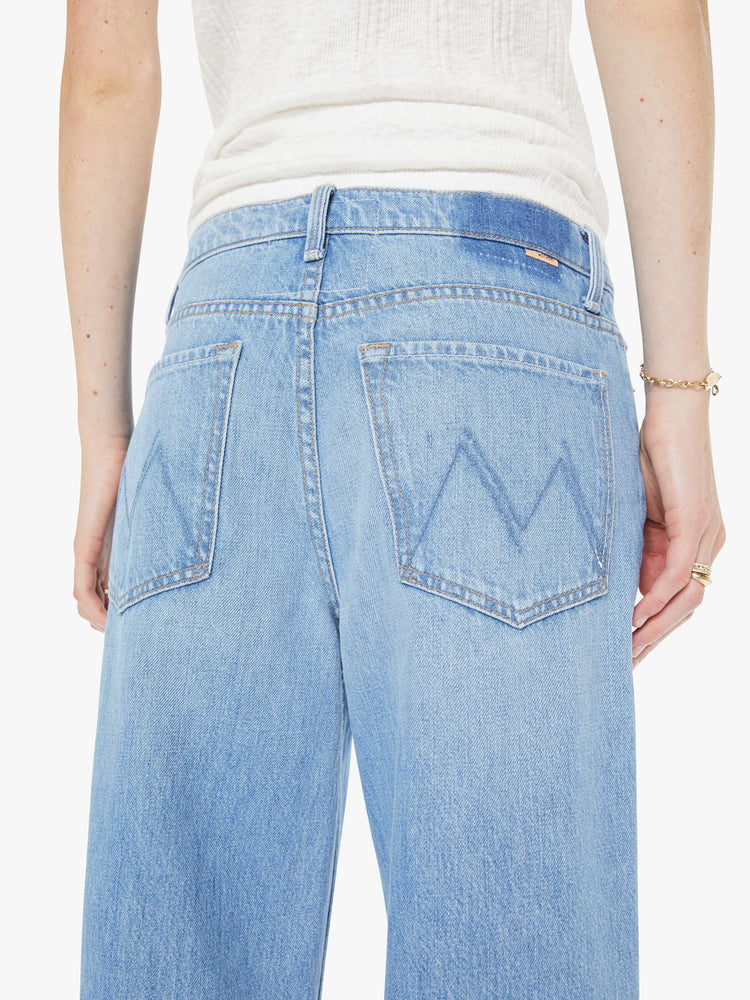 Close up back view of a woman in a light blue high-waisted wide leg jeans with a zip fly, a long 32-inch inseam and loose, low-slung fit.