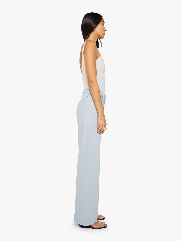 Side view of a woman in a light blue high-waisted wide leg jeans with a zip fly, long 33 1/4-inch inseam and loose, low-slung fit.