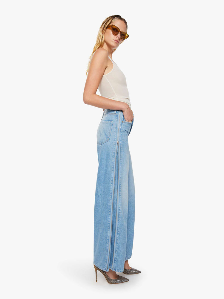 Side view of a woman in a low-slung jeans can be worn two ways with a zipper on the outer seam that can be closed for a more narrow fit, and are designed with a zip fly, loose, wide leg and a long 32-inch inseam with a clean hem. 