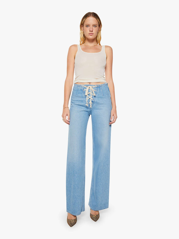 Front view of a woman in a light blue low-slung jeans are designed with a laced closure at the front, a side zip and a wide leg with a 32-inch inseam and a clean hem.