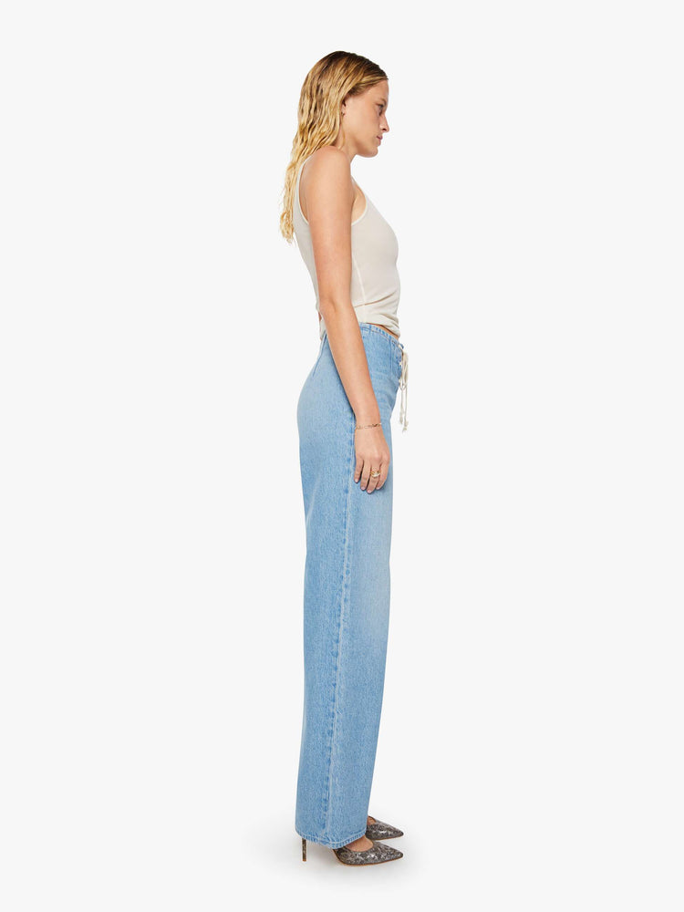 Side view of a woman in a light blue low-slung jeans are designed with a laced closure at the front, a side zip and a wide leg with a 32-inch inseam and a clean hem.