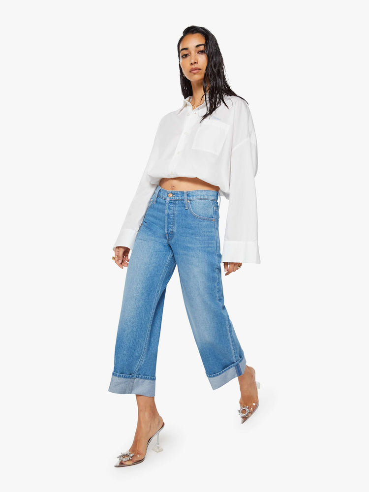 Walking view of a woman in mid blue wide-leg jeans are designed with a button fly and a 26-inch inseam with a cuffed hem.