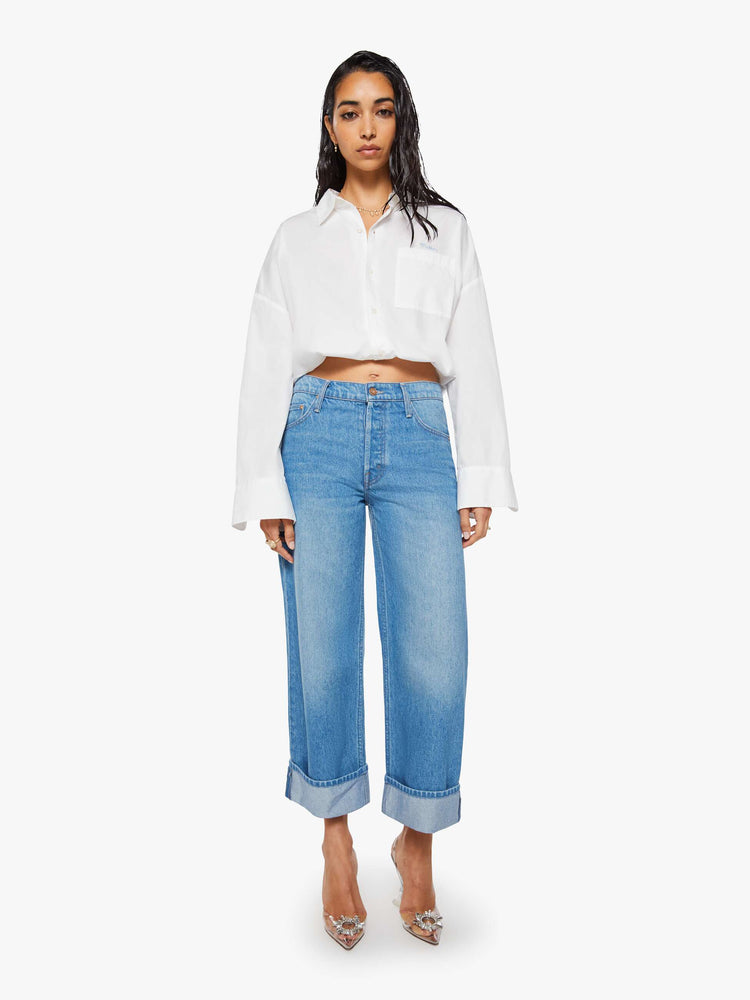 Front view of a woman in mid blue wide-leg jeans are designed with a button fly and a 26-inch inseam with a cuffed hem.