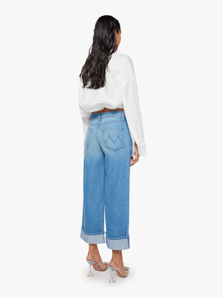 Back view of a woman in mid blue wide-leg jeans are designed with a button fly and a 26-inch inseam with a cuffed hem.