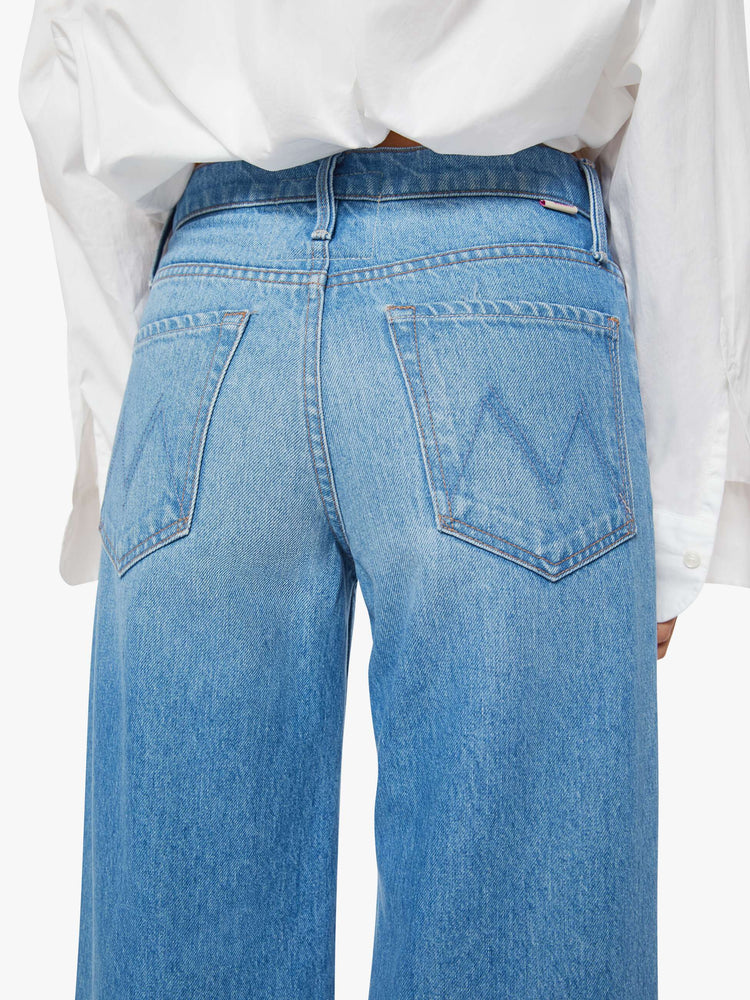 Back close up view of a woman in mid blue wide-leg jeans are designed with a button fly and a 26-inch inseam with a cuffed hem.