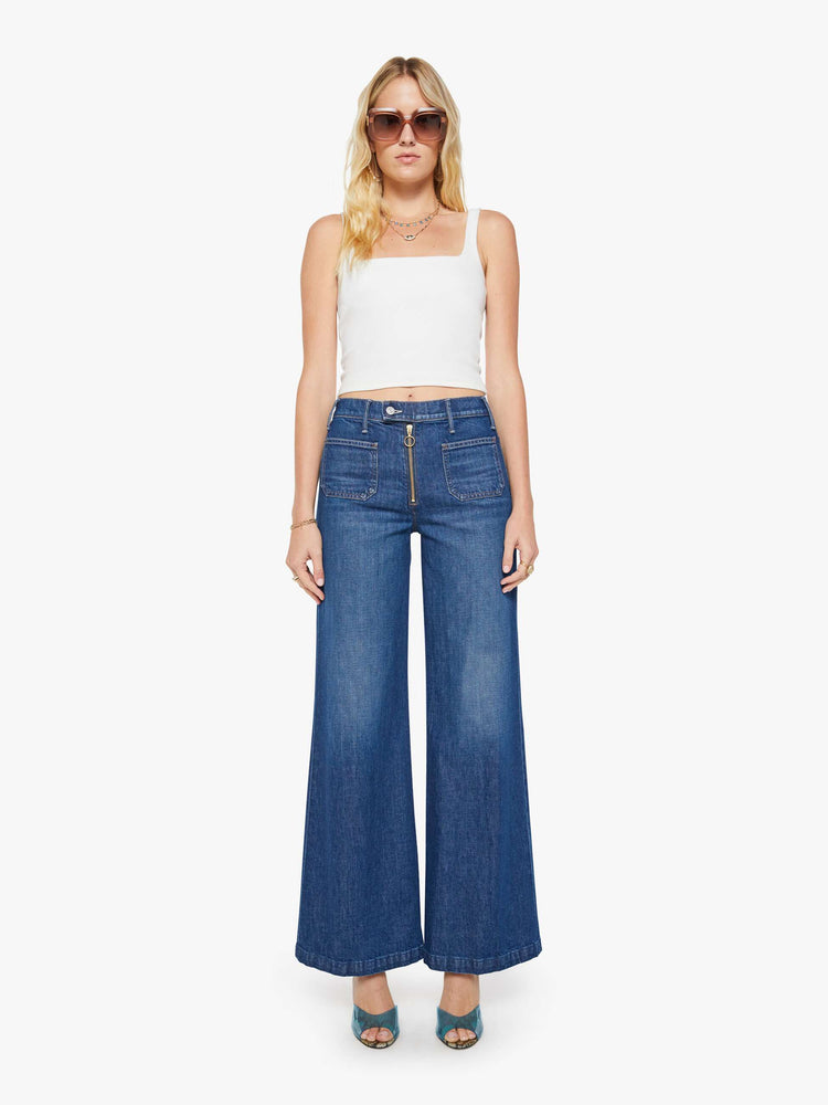 Front view of a woman in a dark blue wide leg jeans with a high rise, exposed zip fly, tabbed waistband, patch pockets and a long 34-inch inseam with a clean hem.