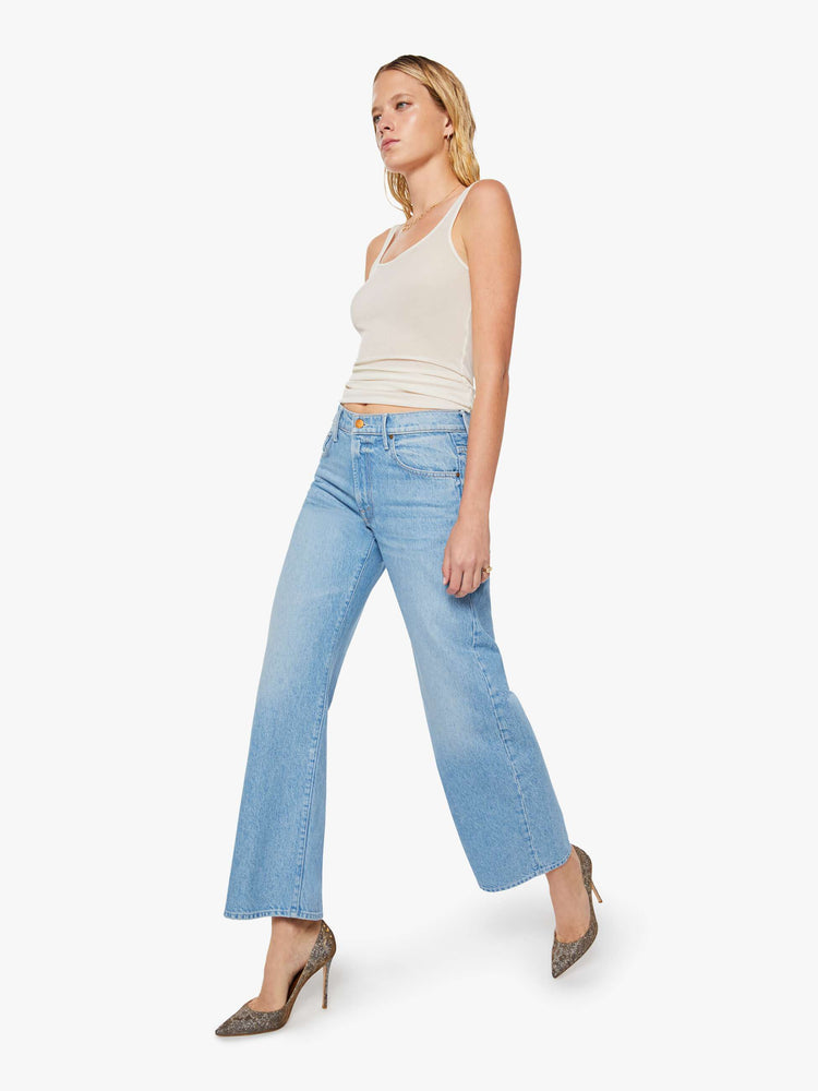 Walking view of a woman in a light blue high-waisted jeans are designed with a zip fly, relaxed fit and a 31-inch inseam with a clean hem.