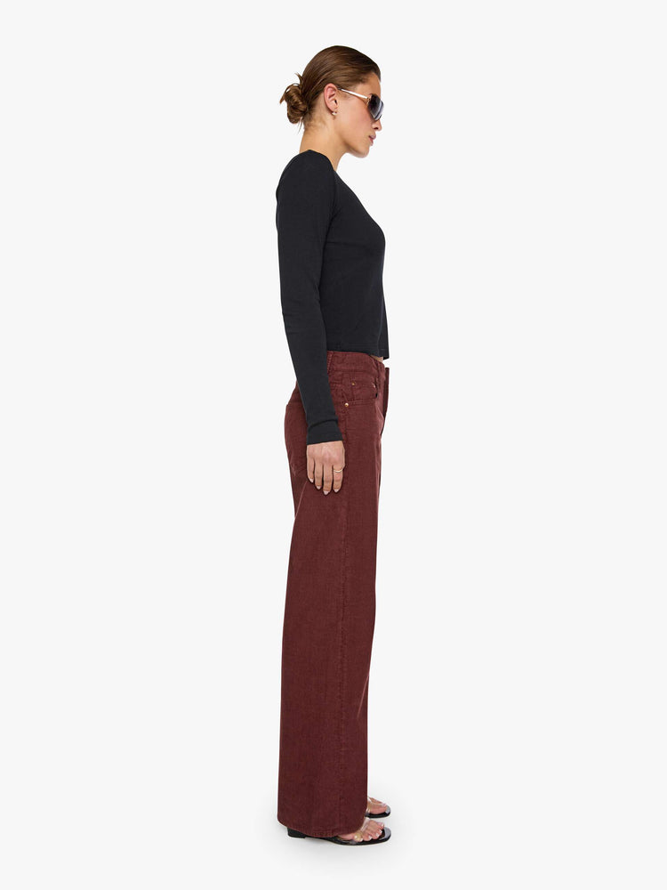 Side angel view of a woman in a merlot corduroy high-waisted jeans are designed with a zip fly, relaxed fit and a 31-inch inseam with a clean hem.
