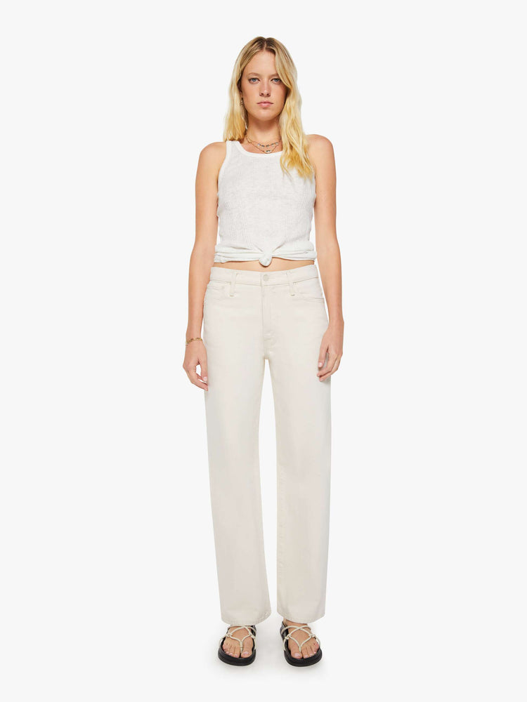 Front view of a woman in creamy white pants designed to sit lower on the hips with a zip fly, loose straight leg and a clean 31-inch inseam.