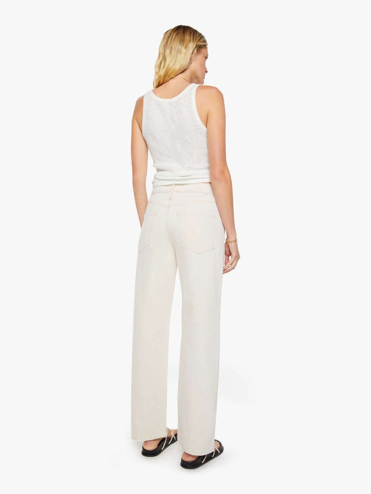 Back view of a woman in creamy white pants designed to sit lower on the hips with a zip fly, loose straight leg and a clean 31-inch inseam.