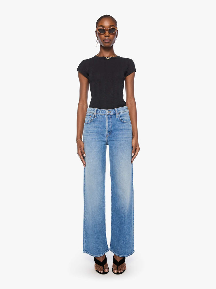 Front view of a woman in a med blue high-waisted wide leg jeans with a zip fly, a long 31-inch inseam and loose, low-slung fit. 