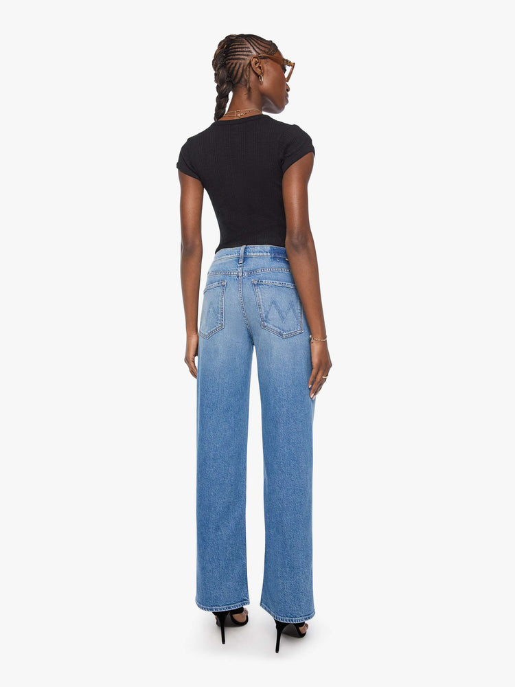 Back view of a woman in a med blue high-waisted wide leg jeans with a zip fly, a long 31-inch inseam and loose, low-slung fit. 