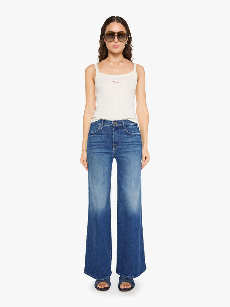 Front view of a woman in a mid blue wide leg jeans with a high rise, zip fly, double-stitched side seam, 32-inch inseam and a clean hem.