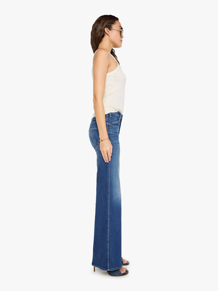 Side view of a woman in a mid blue wide leg jeans with a high rise, zip fly, double-stitched side seam, 32-inch inseam and a clean hem.