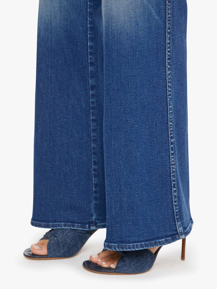Hem view of a woman in a mid blue wide leg jeans with a high rise, zip fly, double-stitched side seam, 32-inch inseam and a clean hem.