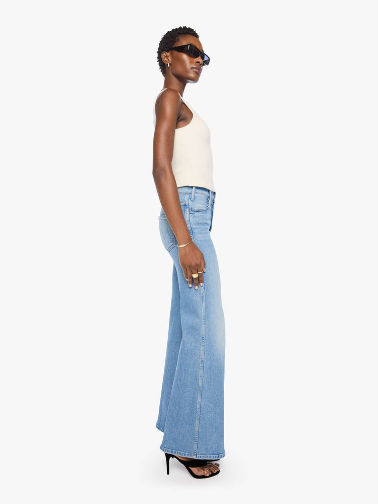 Side view of a woman in a light blue wide leg jeans with a high rise, 32-inch inseam and a clean hem.